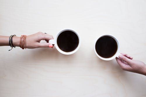 Two People Holding White Mugs