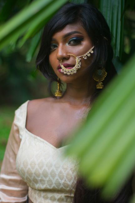 Stunning portrait of a woman with traditional jewelry amidst lush greenery.