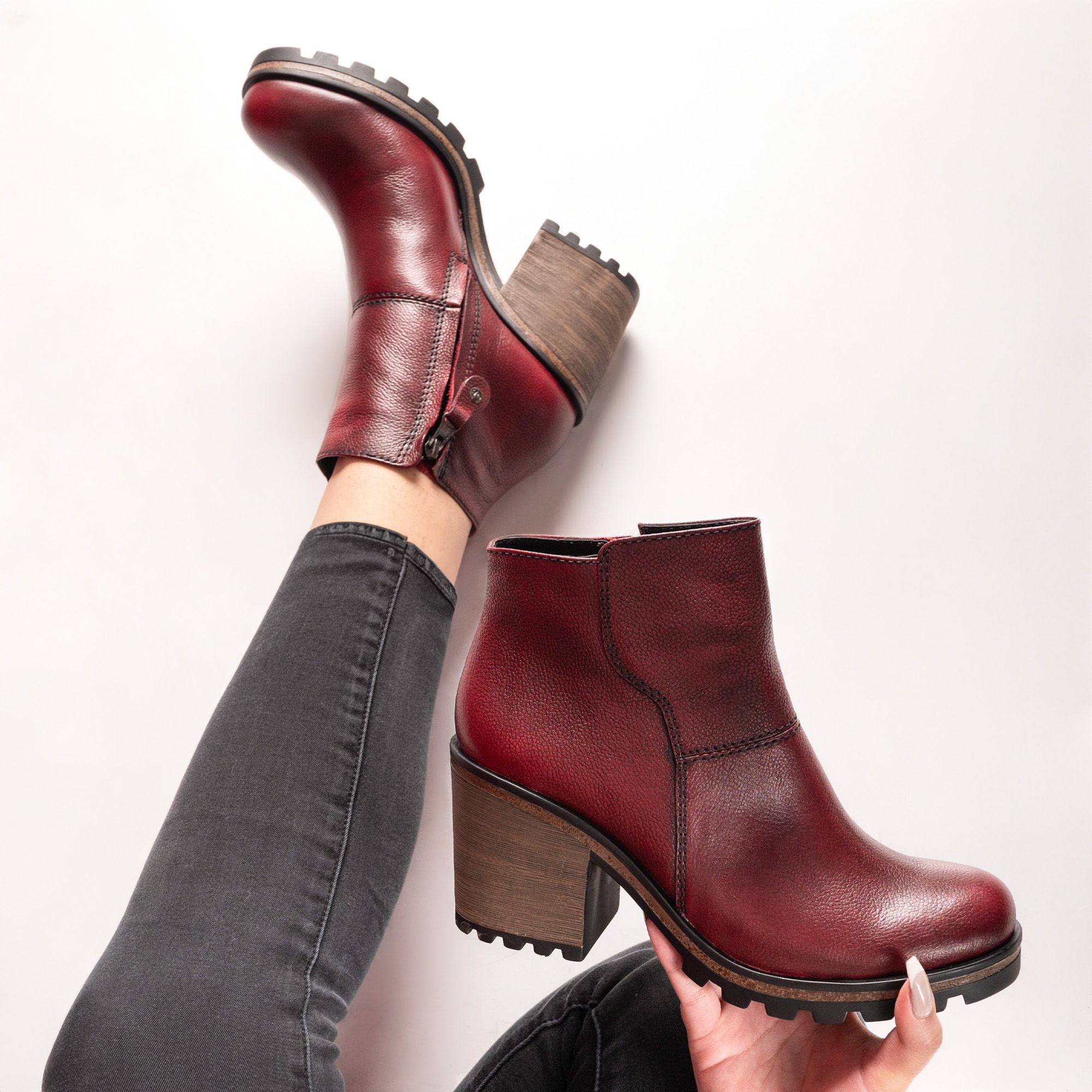 Chic burgundy leather ankle boots with block heel in a fashion-forward pose.