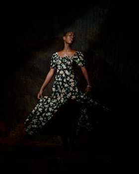 Artsy portrait of a woman in a floral gown, exuding grace and style in a dark setting.