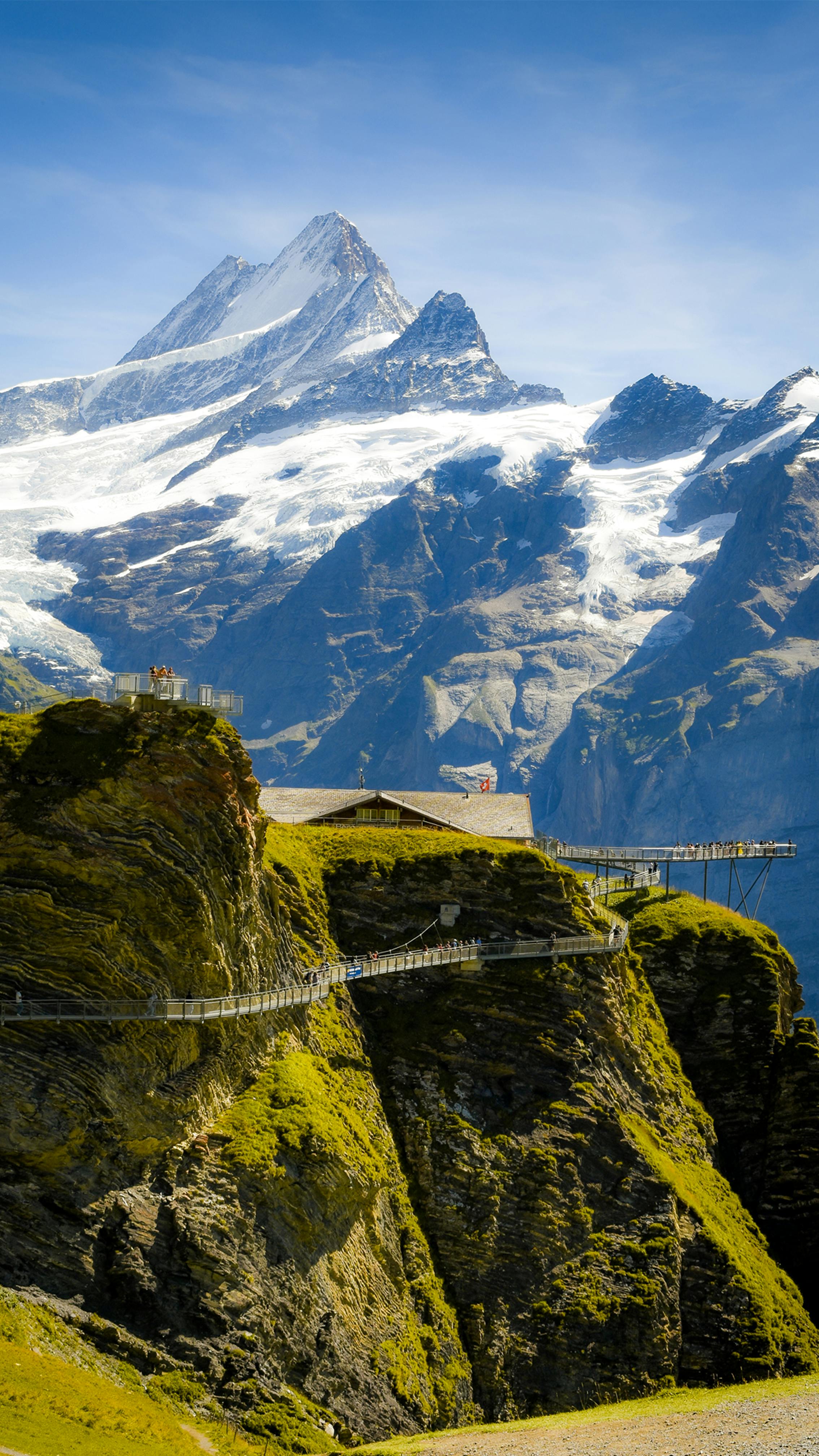 a mountain with a bridge over it and a mountain range in the background