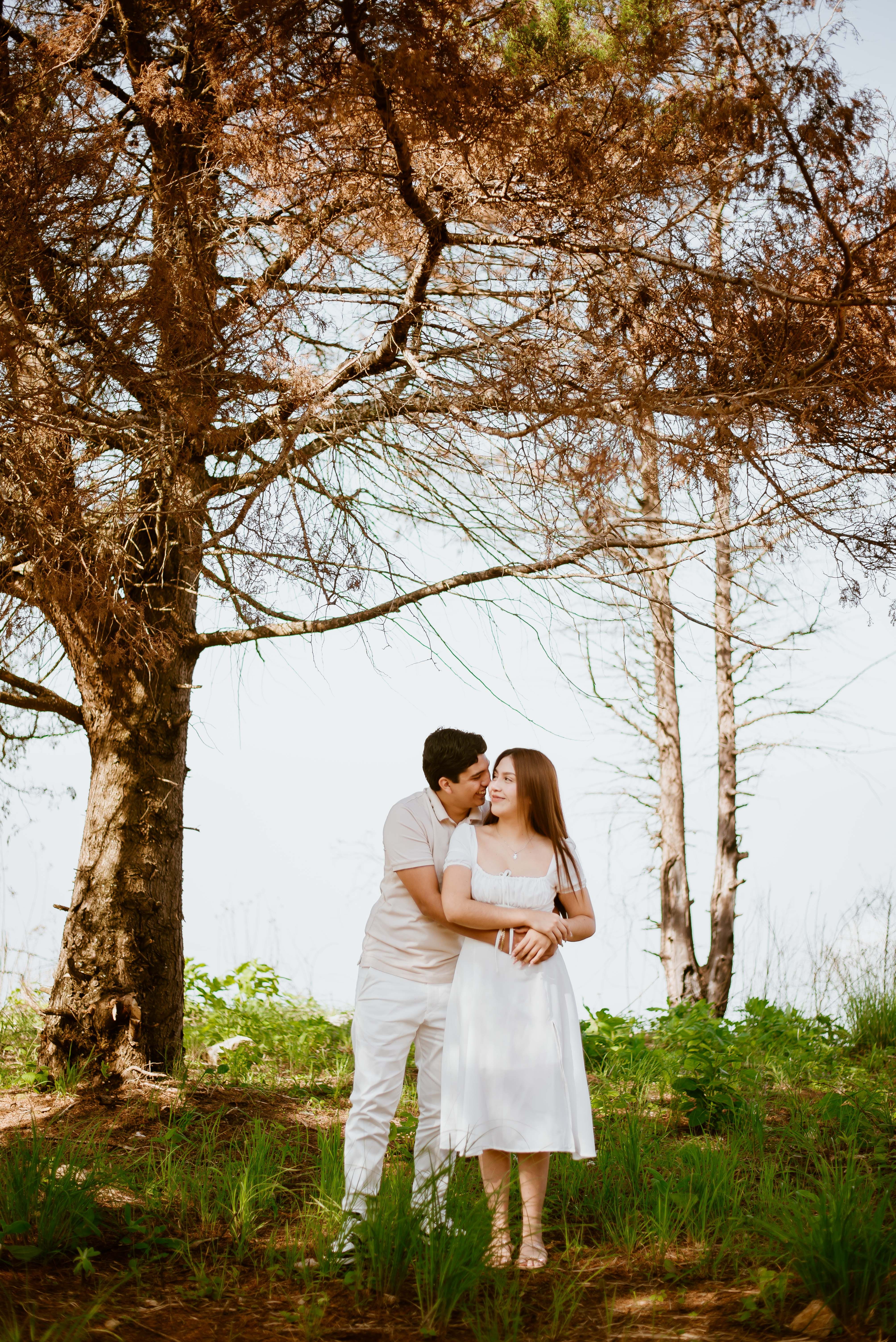 A couple in white standing in front of a tree · Free Stock Photo