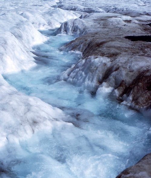 Free A stunning view of glacial meltwater cutting through ice and snow, showcasing nature's power. Stock Photo