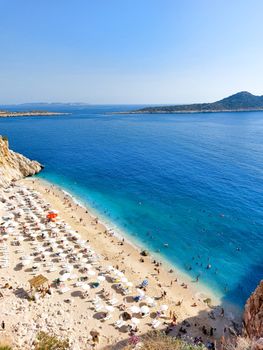 A beautiful beach scene at Antalya with turquoise waters and sunbathing visitors enjoying the summer sun.