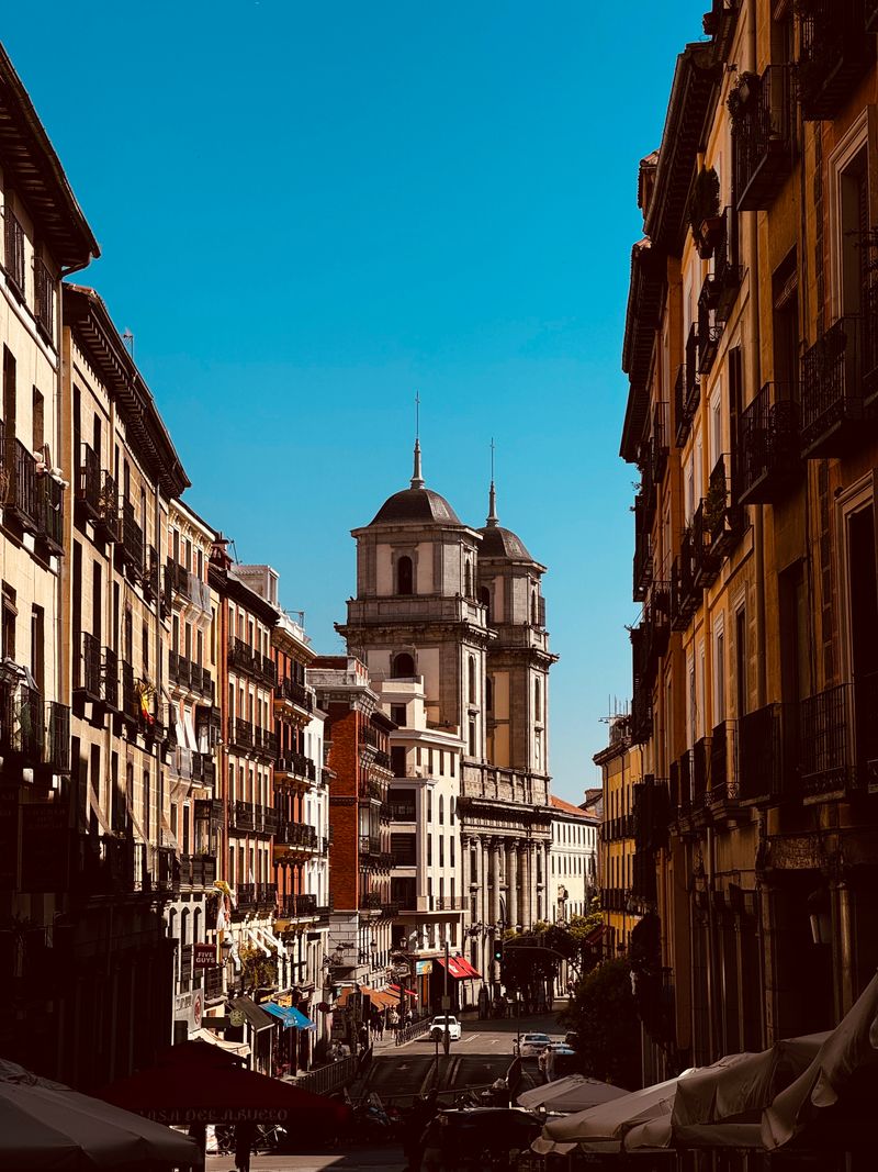 Calle del casco viejo de Madrid con una cúpula al fondo