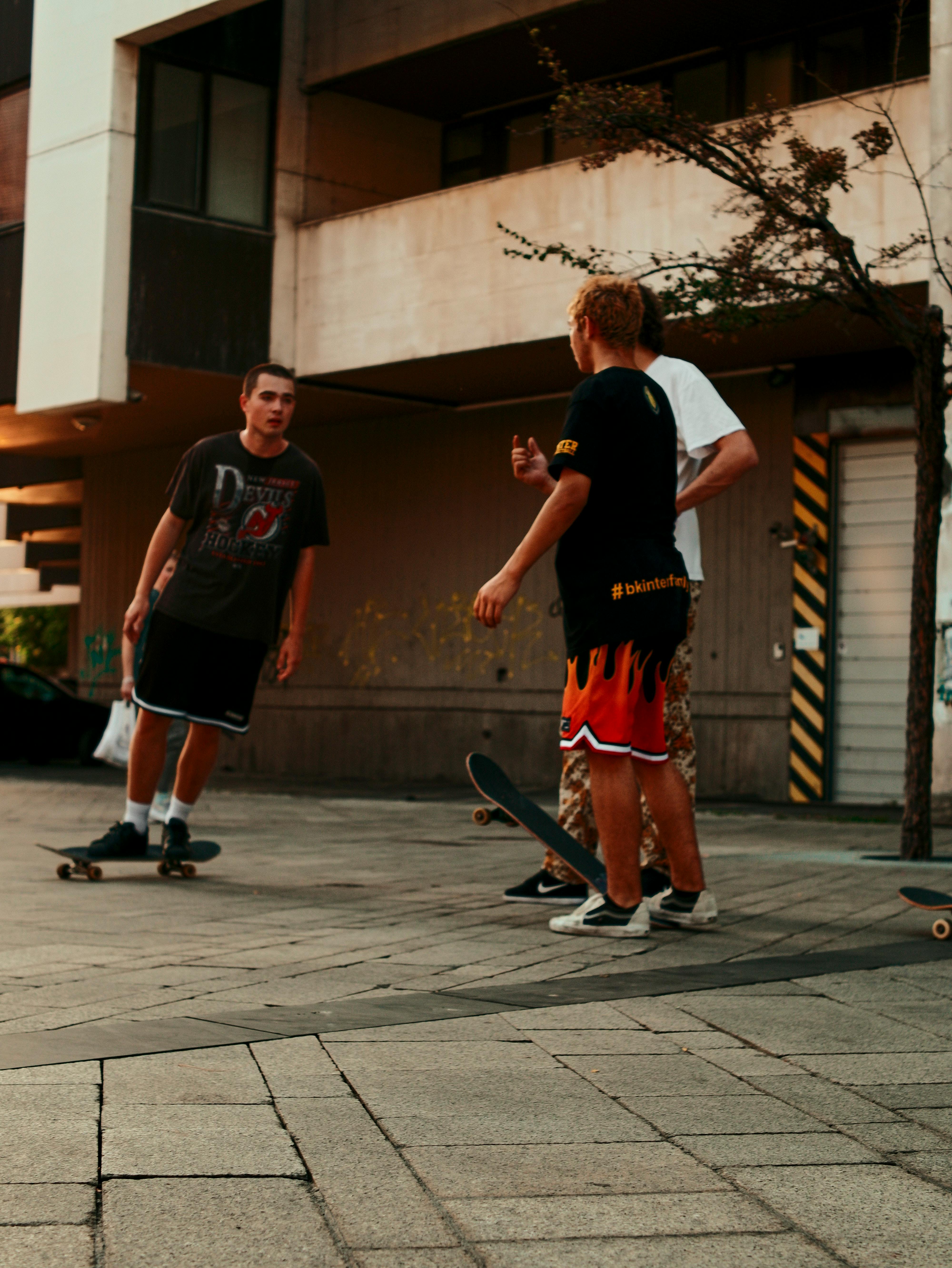 three men are standing on a sidewalk with skateboards