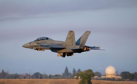 A fighter jet is flying over a field