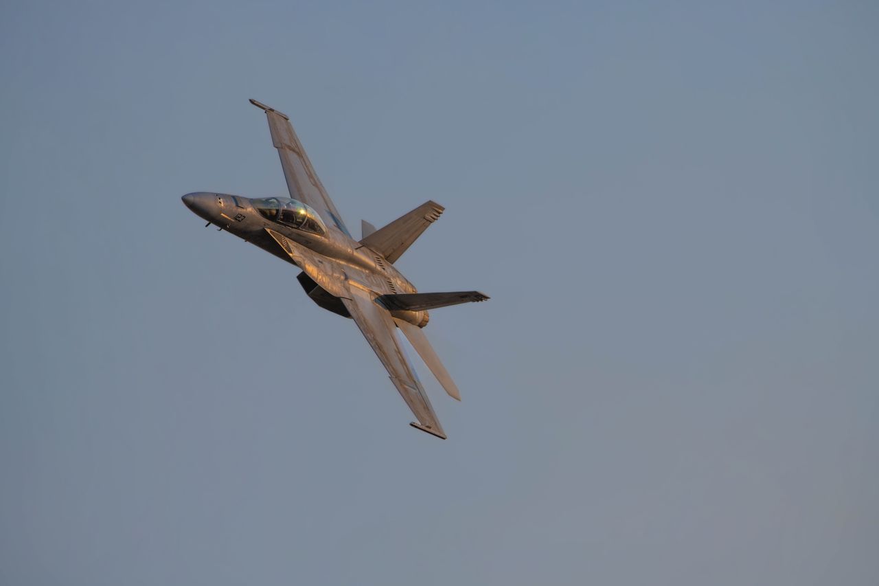 a military jet performing an aerobatic maneuver in clear skies during