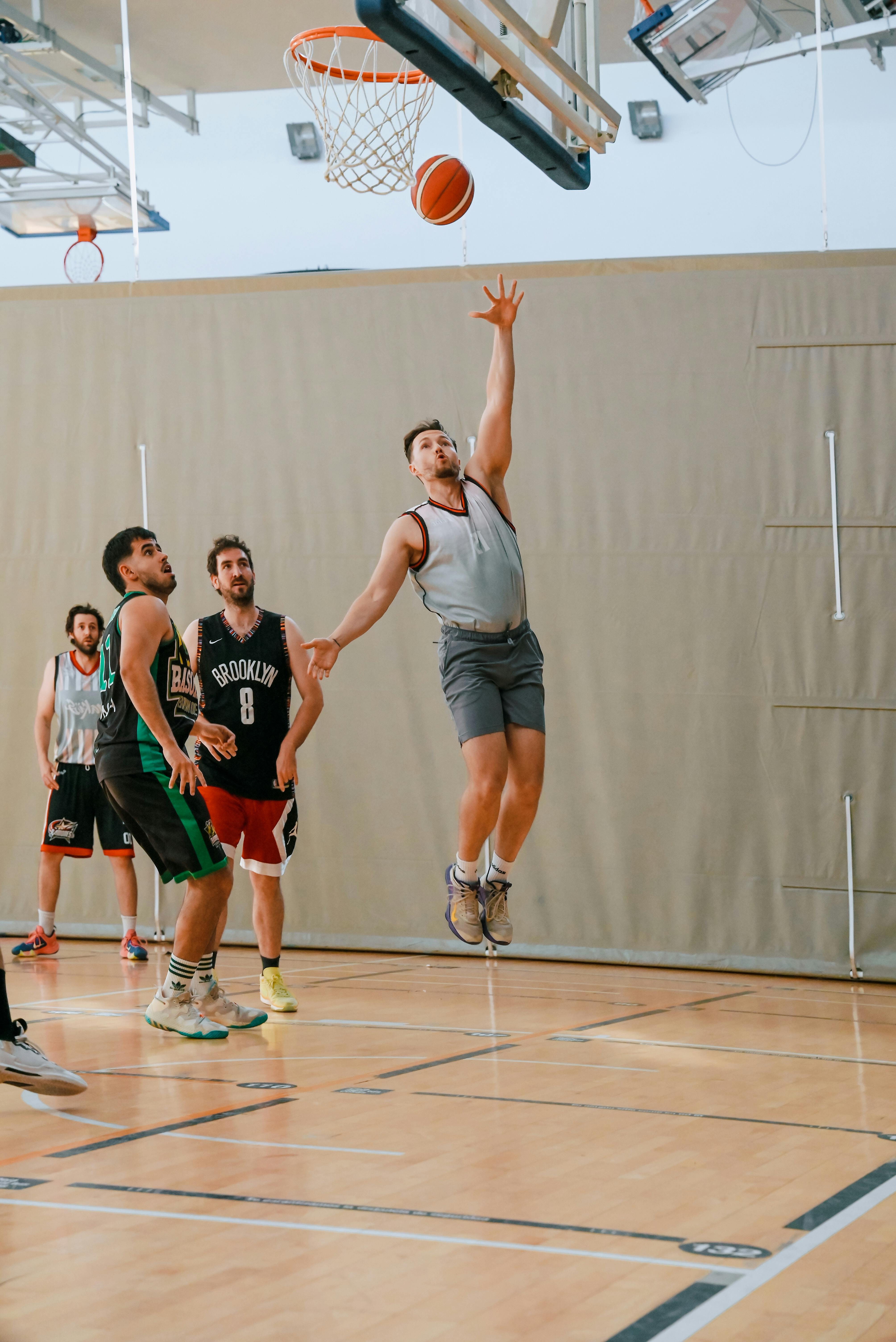 a man in a grey shirt is jumping to block a basketball