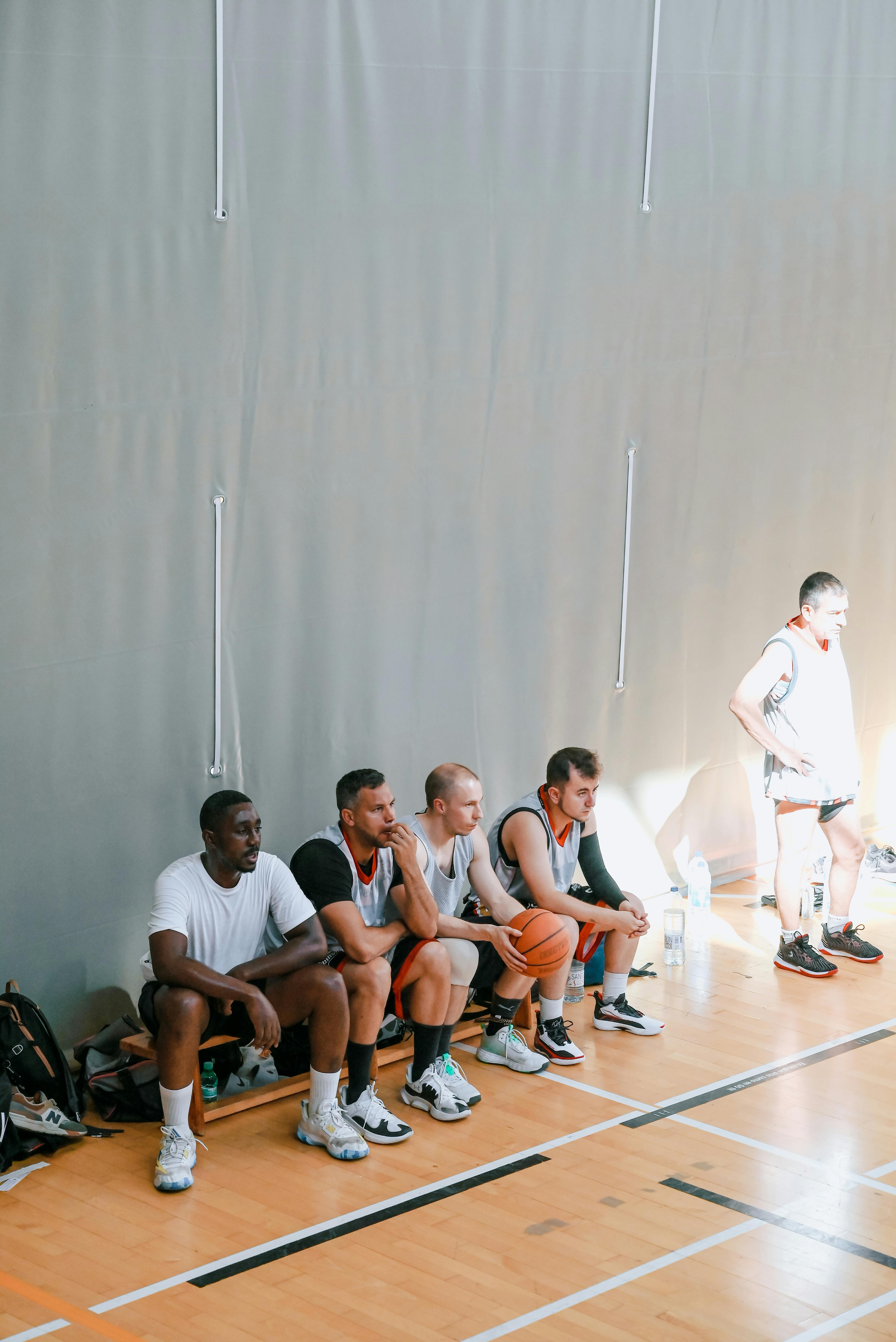 a group of men sitting on the bench in a gym