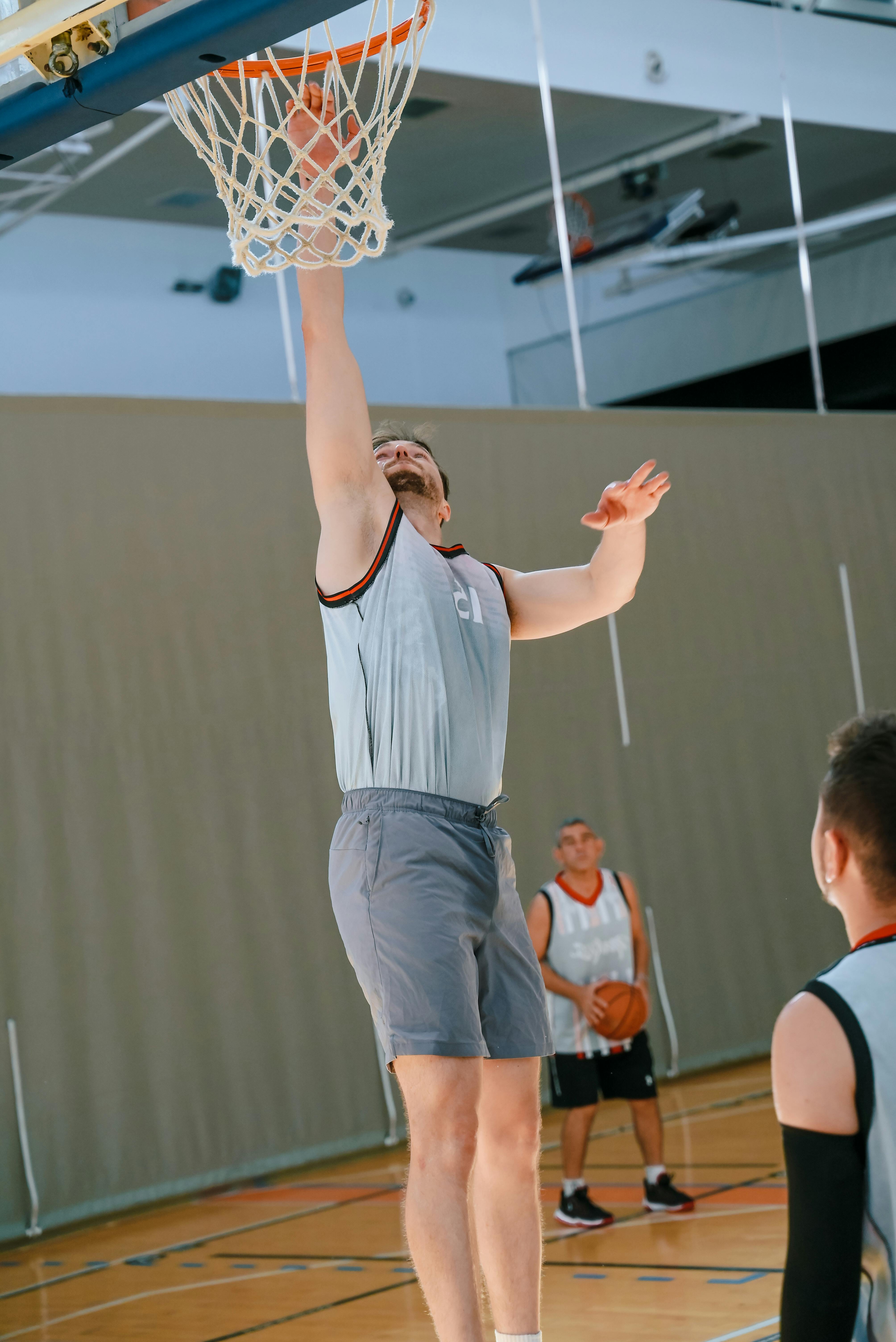 a man in grey shorts is dunking a basketball