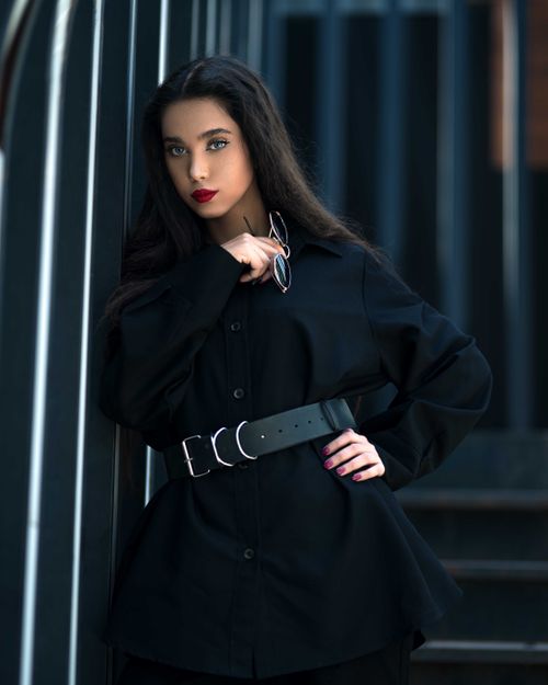 Free Portrait of a stylish woman in a black belted outfit, exuding elegance. Stock Photo