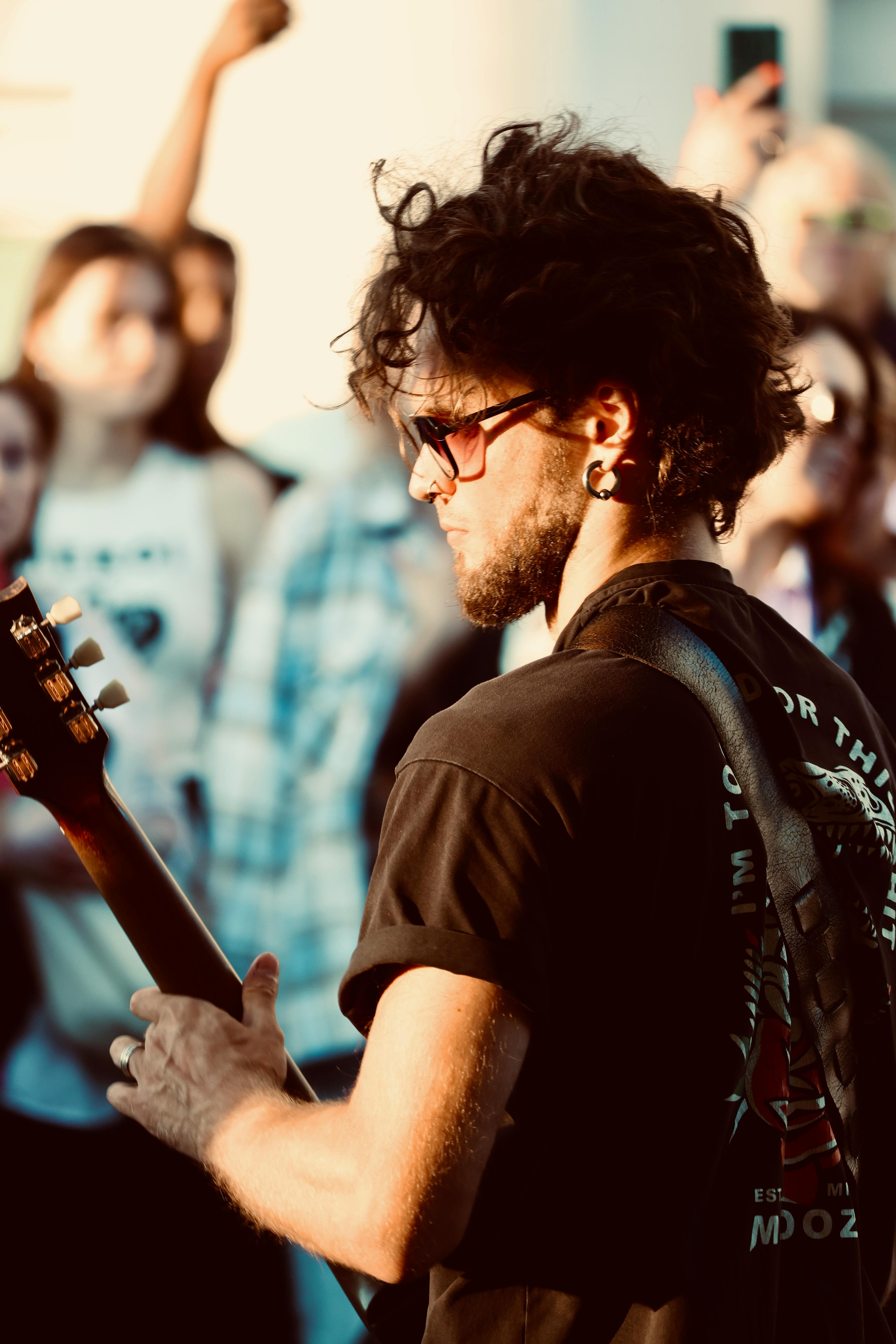 a man with curly hair playing a guitar