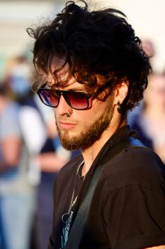 A stylish musician performs with sunglasses at an outdoor event.