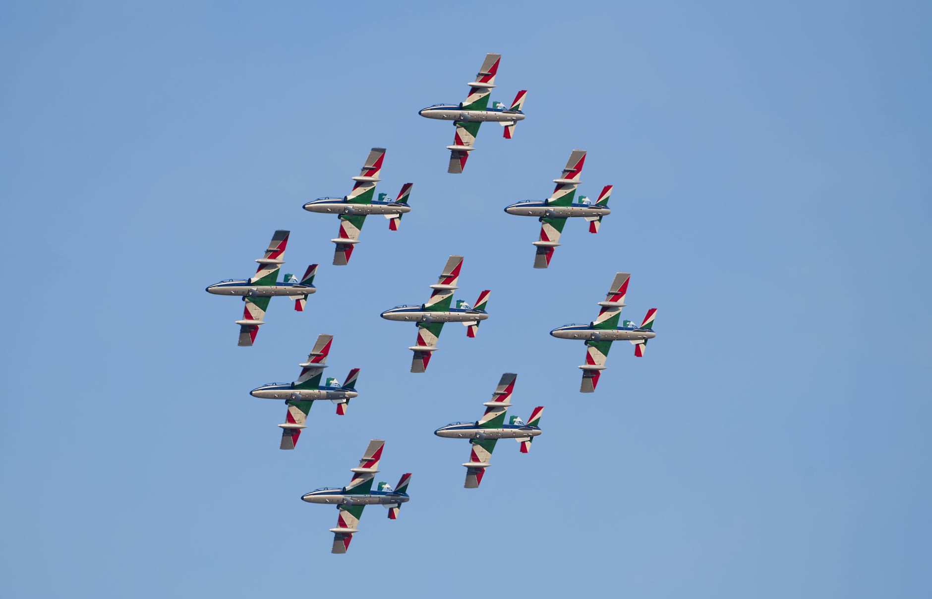 Aerial view of a military jet team performing a precise aerobatic formation under clear skies.