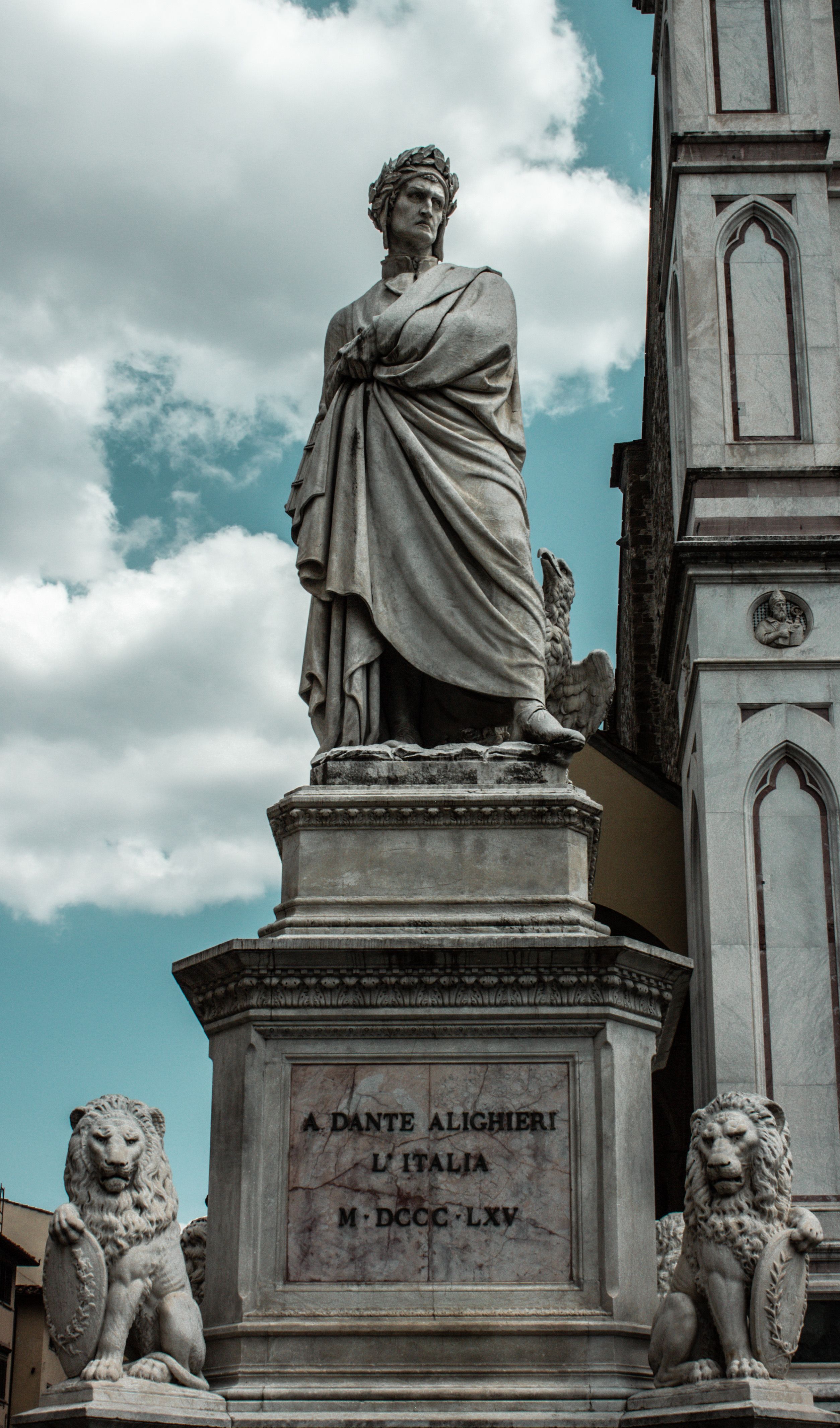 Marble statue of Dante Alighieri against a cloudy sky in Florence, Italy.