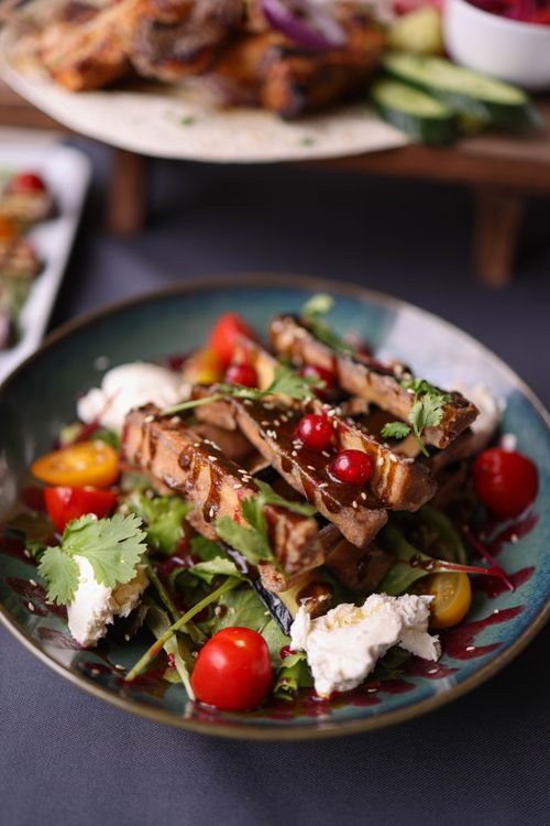 Free Delicious grilled meat served on a bed of fresh greens and vegetables, topped with cheese and herbs. Stock Photo