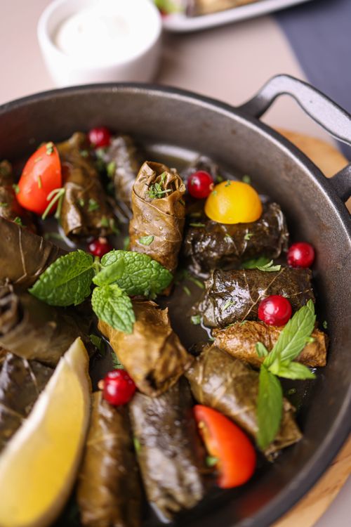 Free Close-up of delicious stuffed grape leaves garnished with tomatoes and herbs. Stock Photo