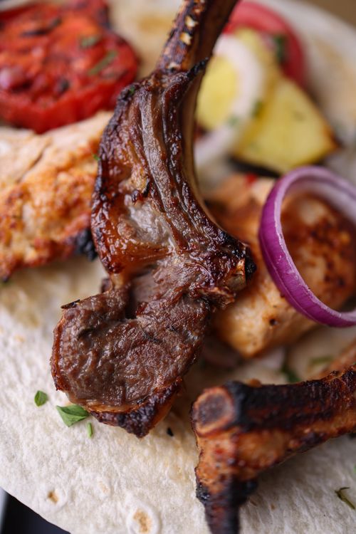 Free Close-up of a grilled lamb chop on a plate with vegetables and tortilla. Stock Photo