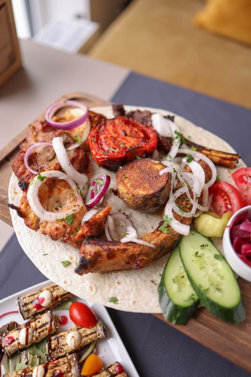 Free Appetizing platter of grilled meats, vegetables, and flatbread served with fresh garnishes. Stock Photo