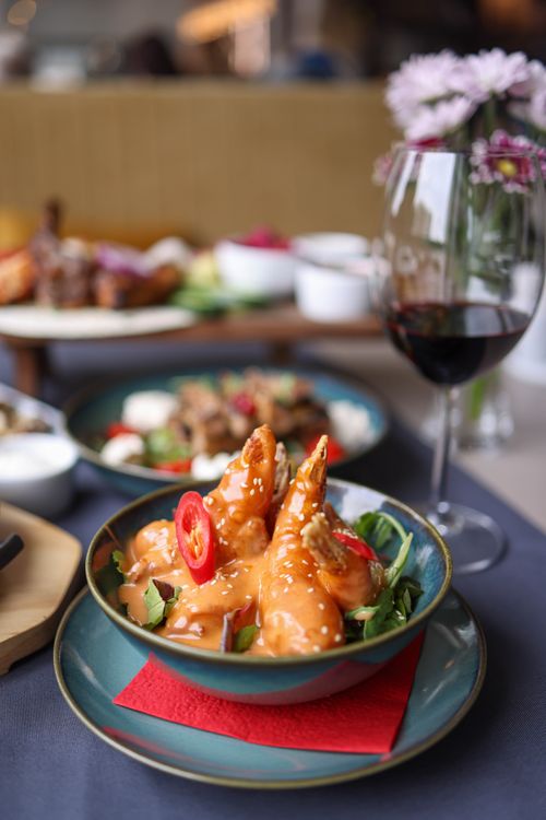 Free Savory shrimp dish garnished with chili peppers accompanied by red wine in a fine dining atmosphere. Stock Photo