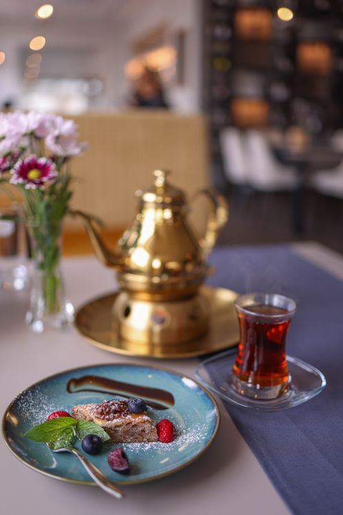 Free Luxurious breakfast setup with a golden teapot, berry-topped pastry, and tea in a refined dining atmosphere. Stock Photo