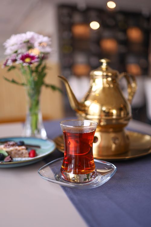 Free Luxury tea setup with gold teapot, elegant glass cup, and flowers creating a classic atmosphere. Stock Photo