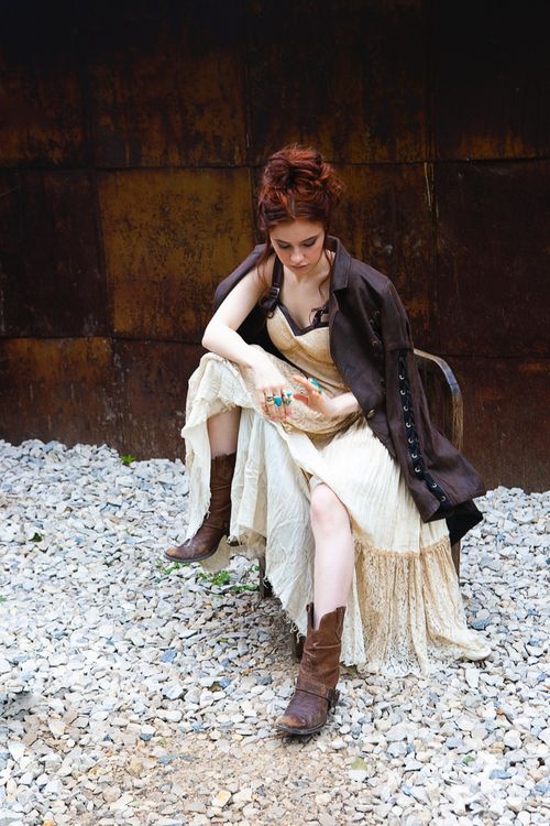A woman in a dress and boots sitting on a rock · Free Stock Photo