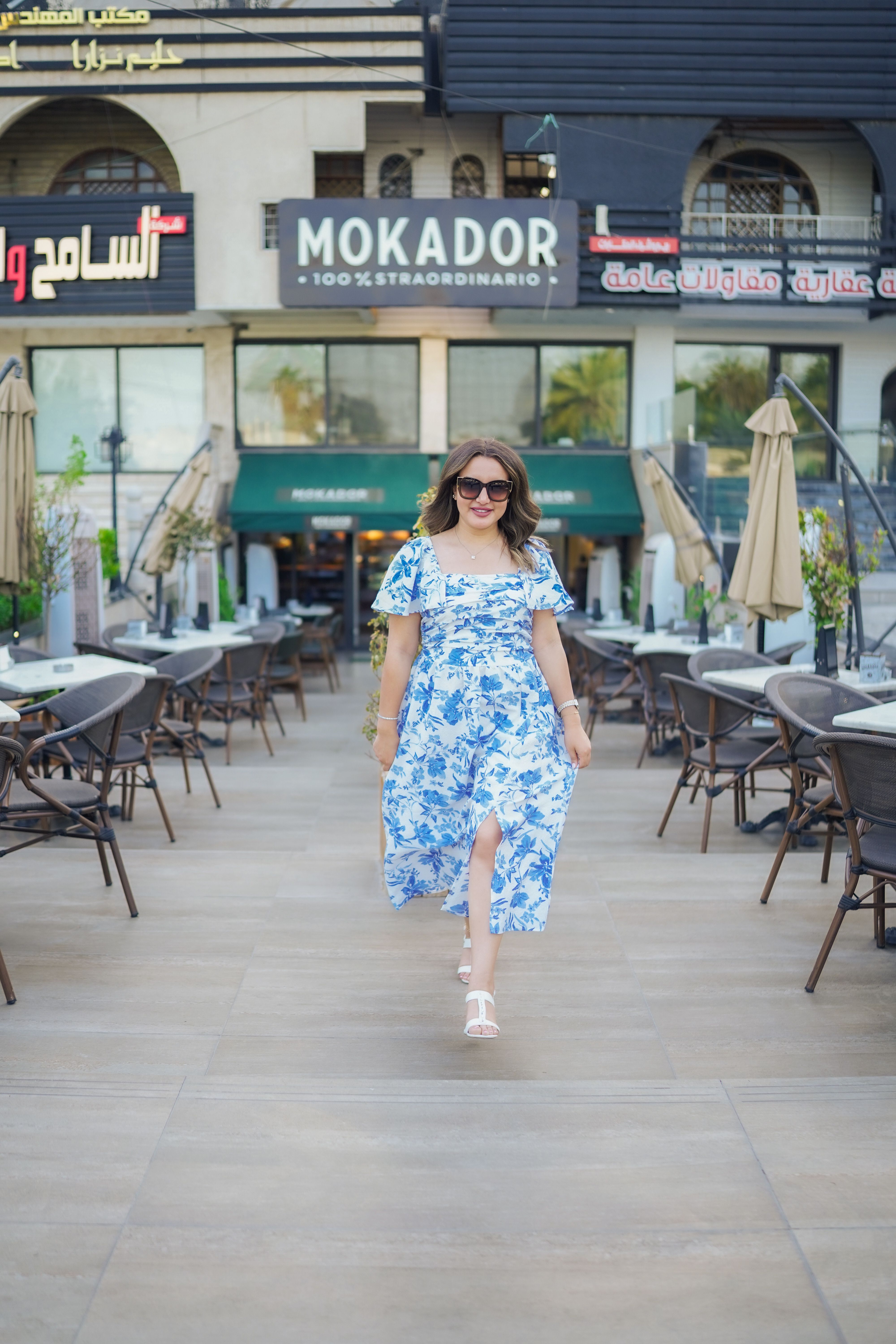 A woman in a blue floral dress walks down a sidewalk · Free Stock Photo
