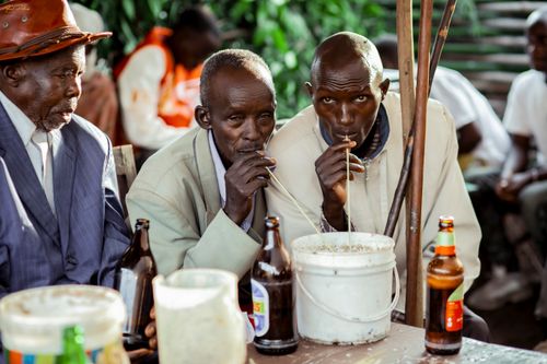 Free Elderly men enjoying a traditional drink from a bucket outdoors, capturing cultural gathering vibes. Stock Photo