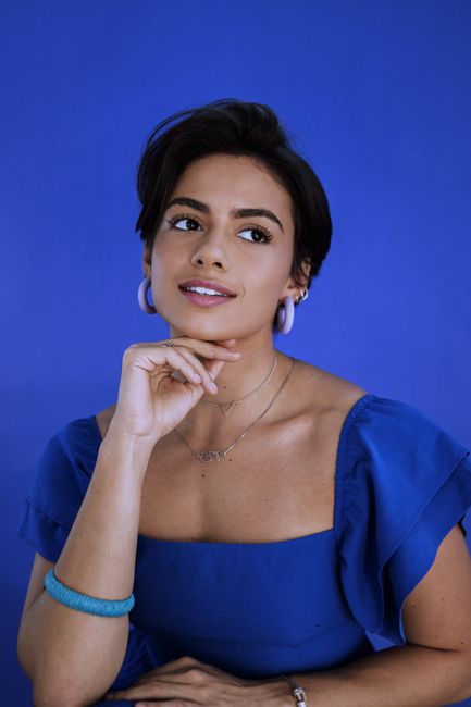 Portrait of a woman in blue attire with elegant jewelry, exuding glamour and charm.