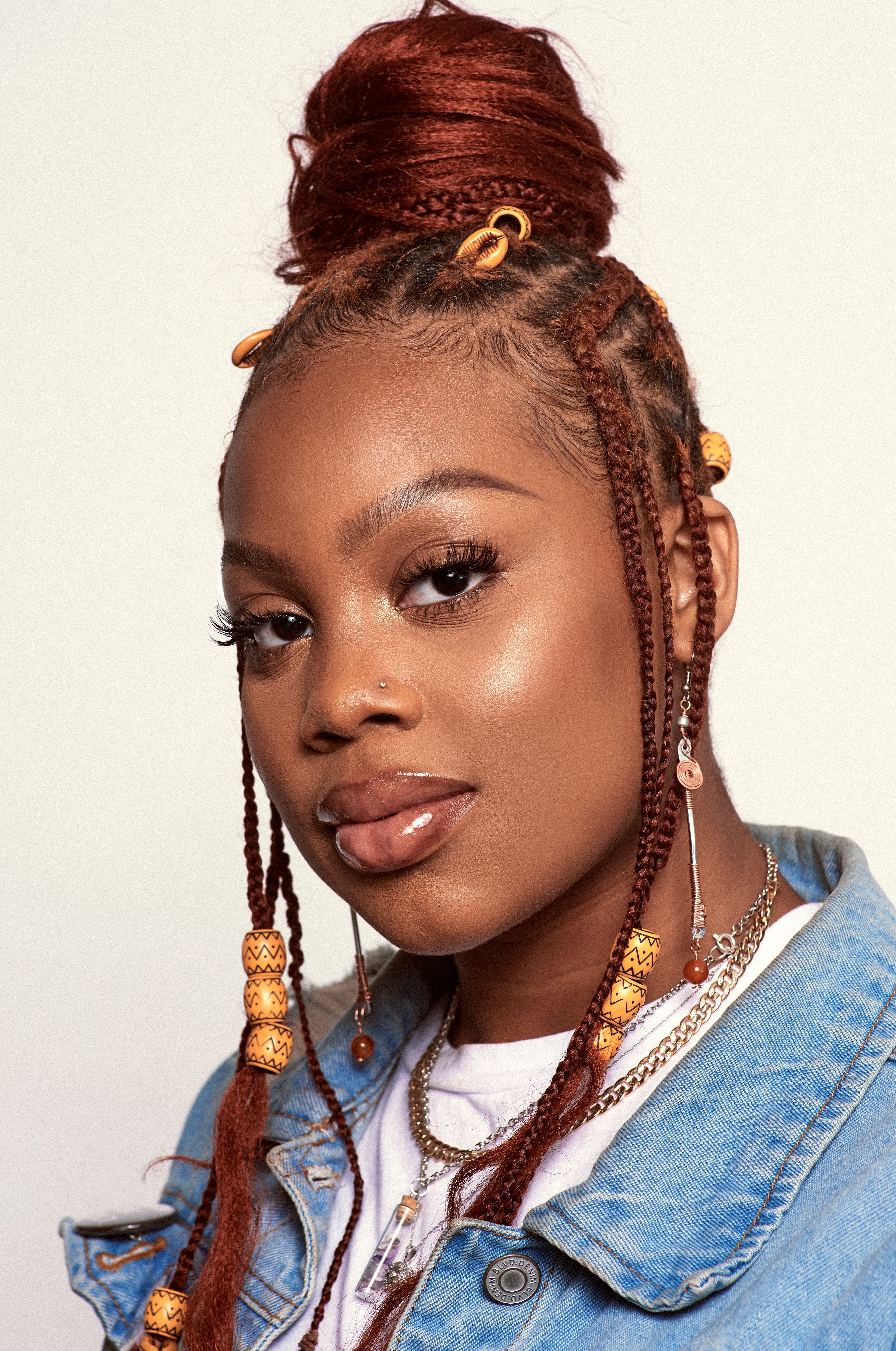 Studio portrait of a woman with braided hair and stylish earrings, showcasing modern fashion.