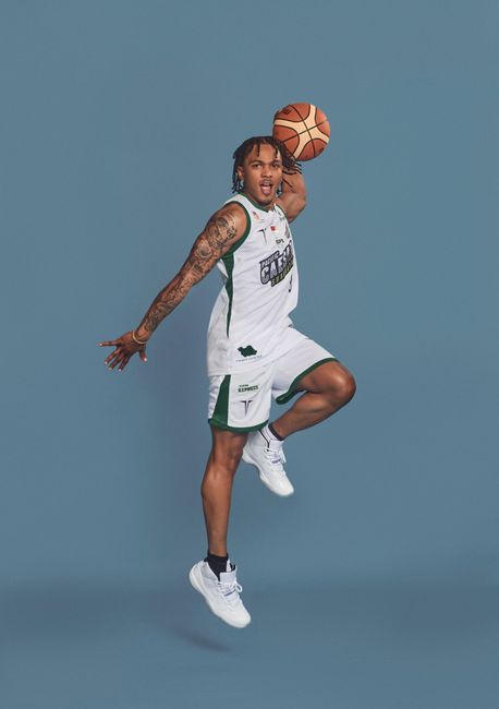 A professional athlete performing a slam dunk during an energetic basketball photo shoot.