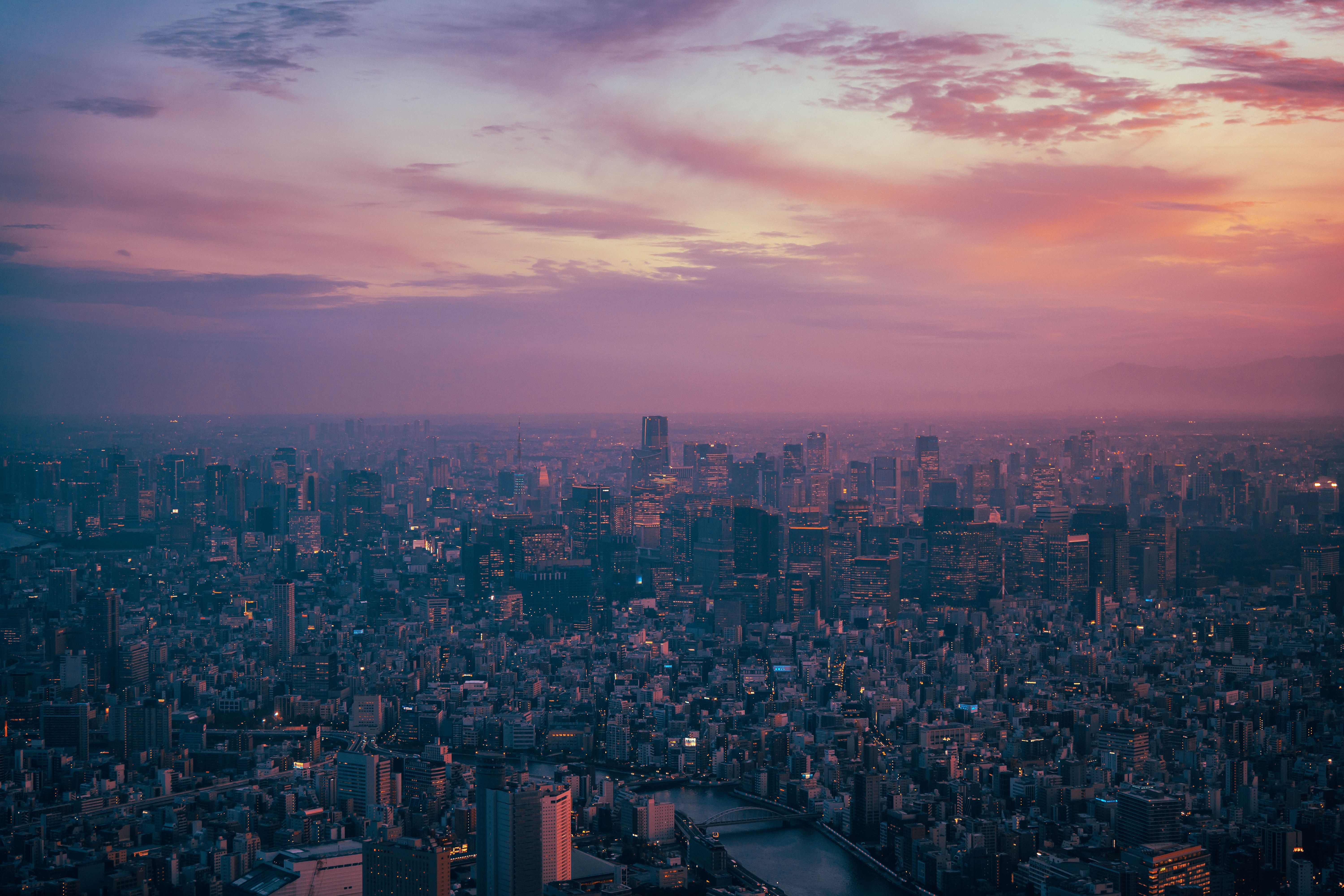 A breathtaking aerial view of Tokyo's skyline at twilight showcasing vibrant neon lights and a serene sunset.
