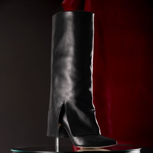Free Stylish black leather boot with red background in a studio setting. Stock Photo