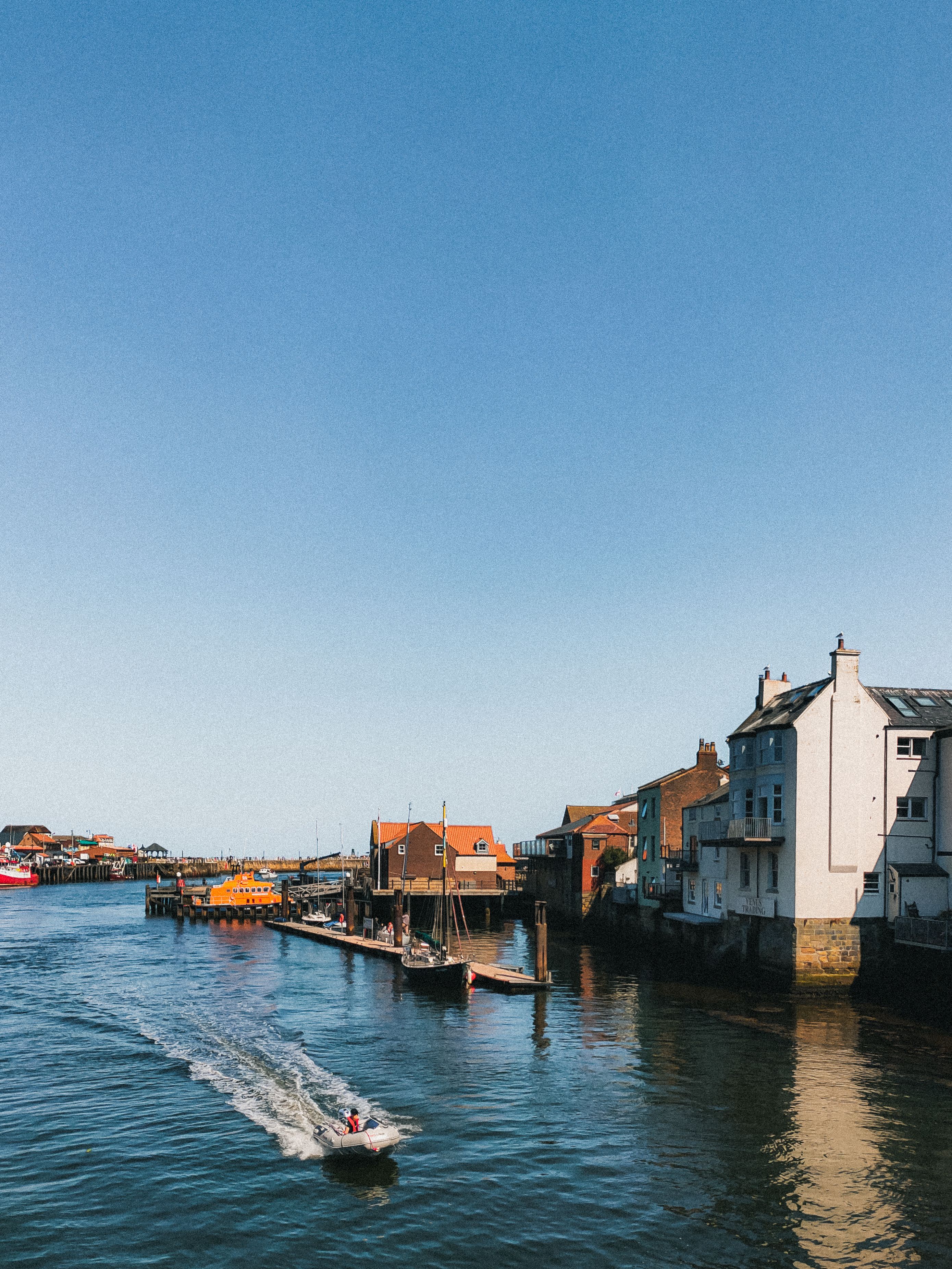 Scenic view of a charming small town by the waterfront with boats and bright blue sky, perfect for travel inspirations.
