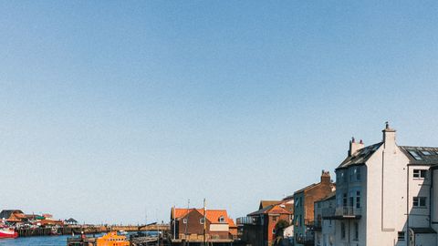 Scenic view of a charming small town by the waterfront with boats and bright blue sky, perfect for travel inspirations.
