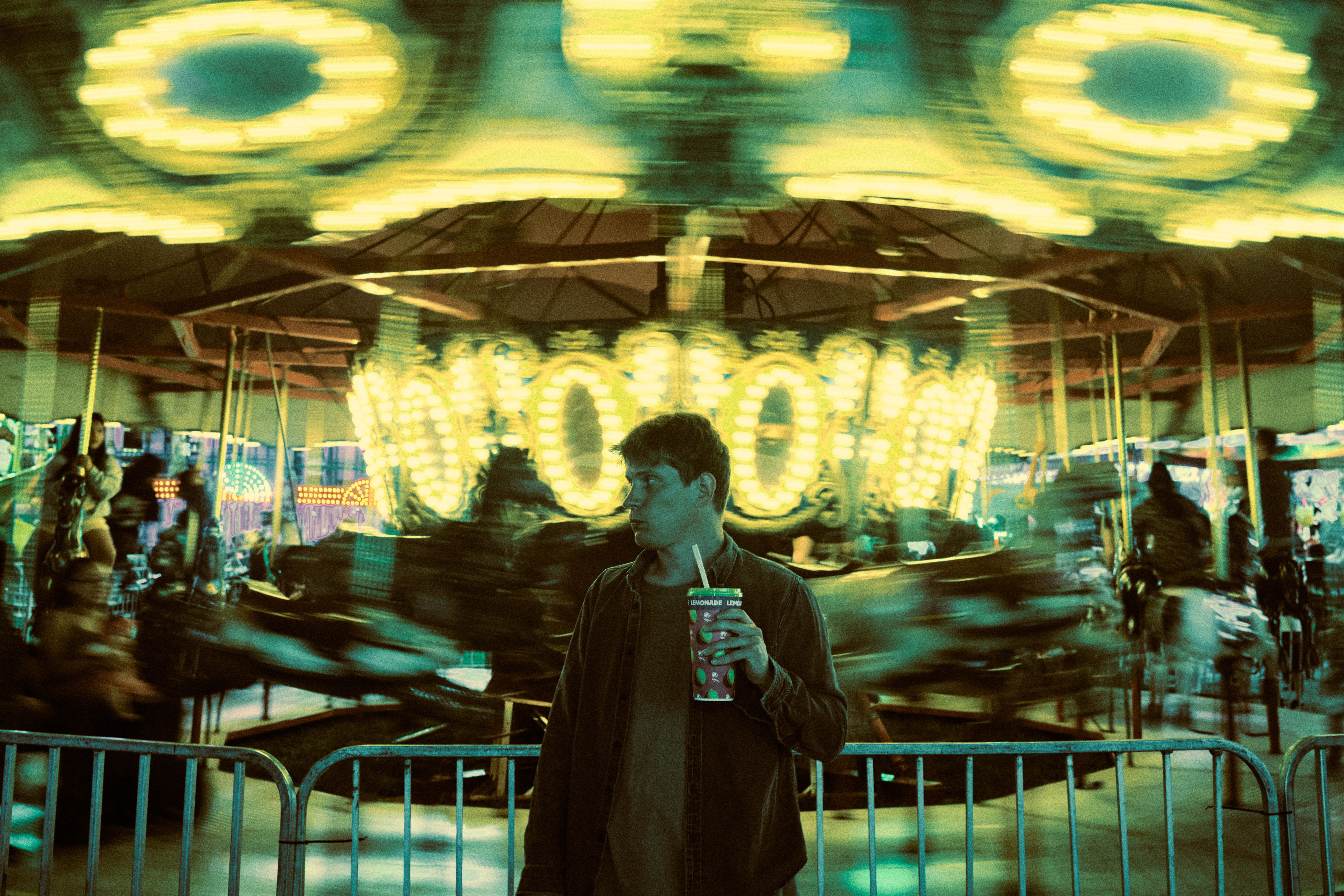 A man enjoying a drink at a vibrant carousel at night, Arlington Heights.