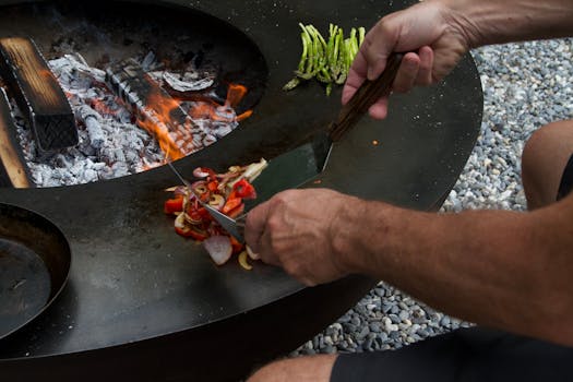 Man grilling vegetables on an outdoor fire pit for a rustic culinary experience.