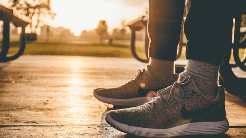 Close-up of sneakers on person standing outdoors at sunrise in a Chicago park.