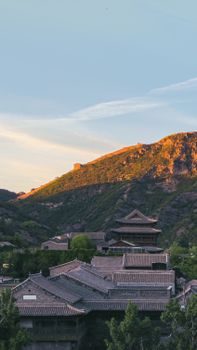 Beautiful sunset over traditional Chinese architecture and mountains in Beijing, China.