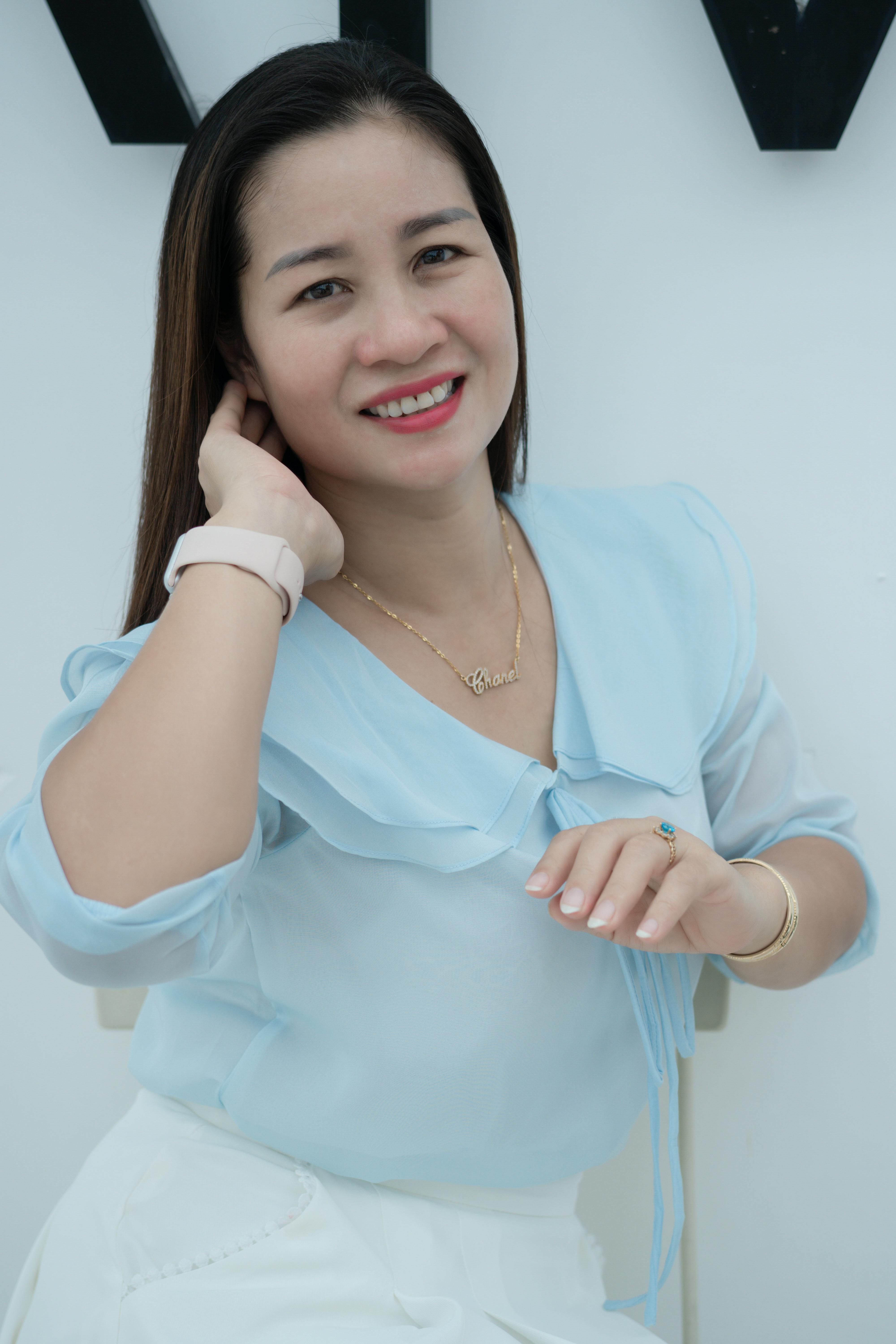 Portrait of a smiling woman wearing a light blue blouse, relaxing indoors.