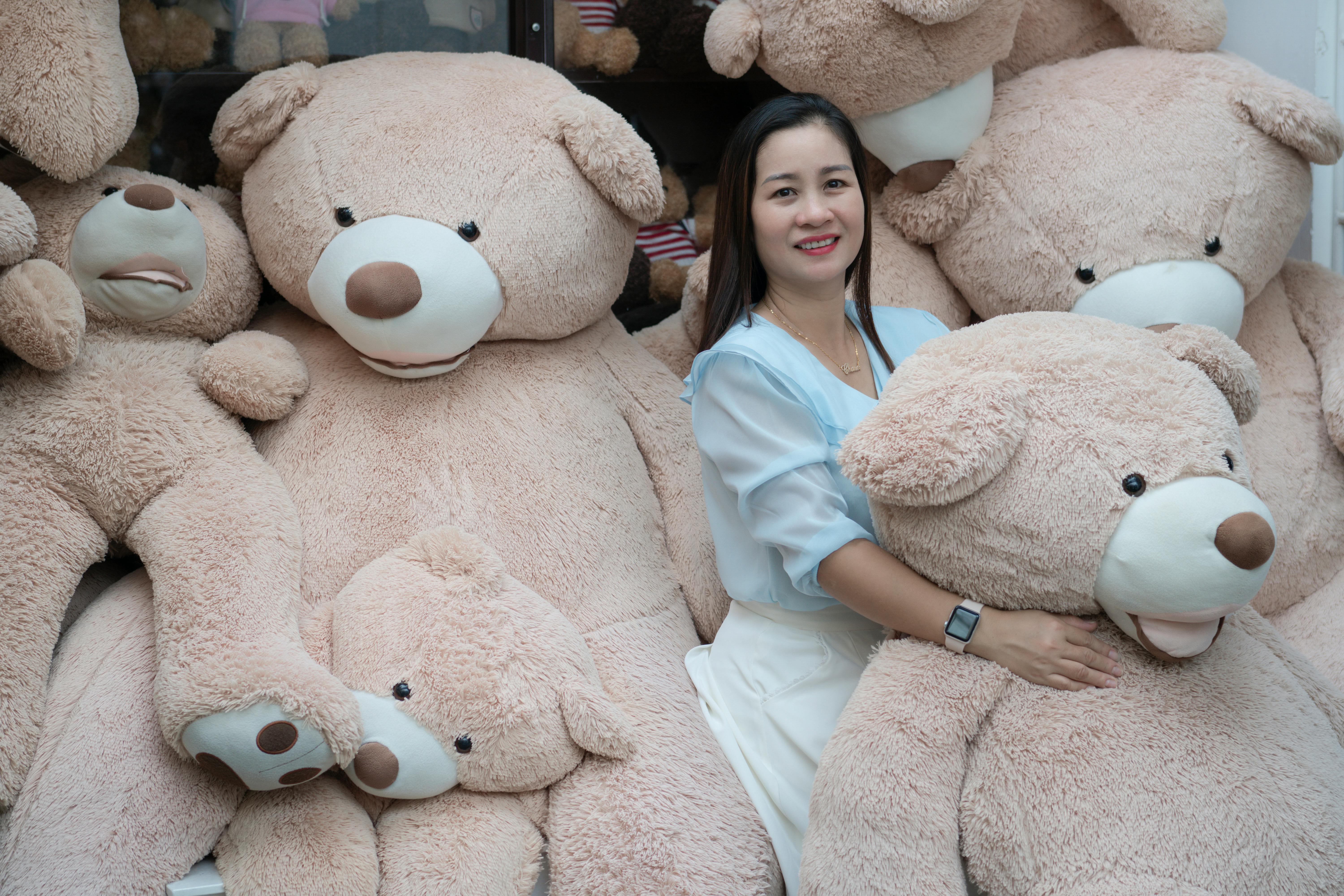 A woman happily poses with large plush teddy bears, showcasing a cozy and joyful scene.