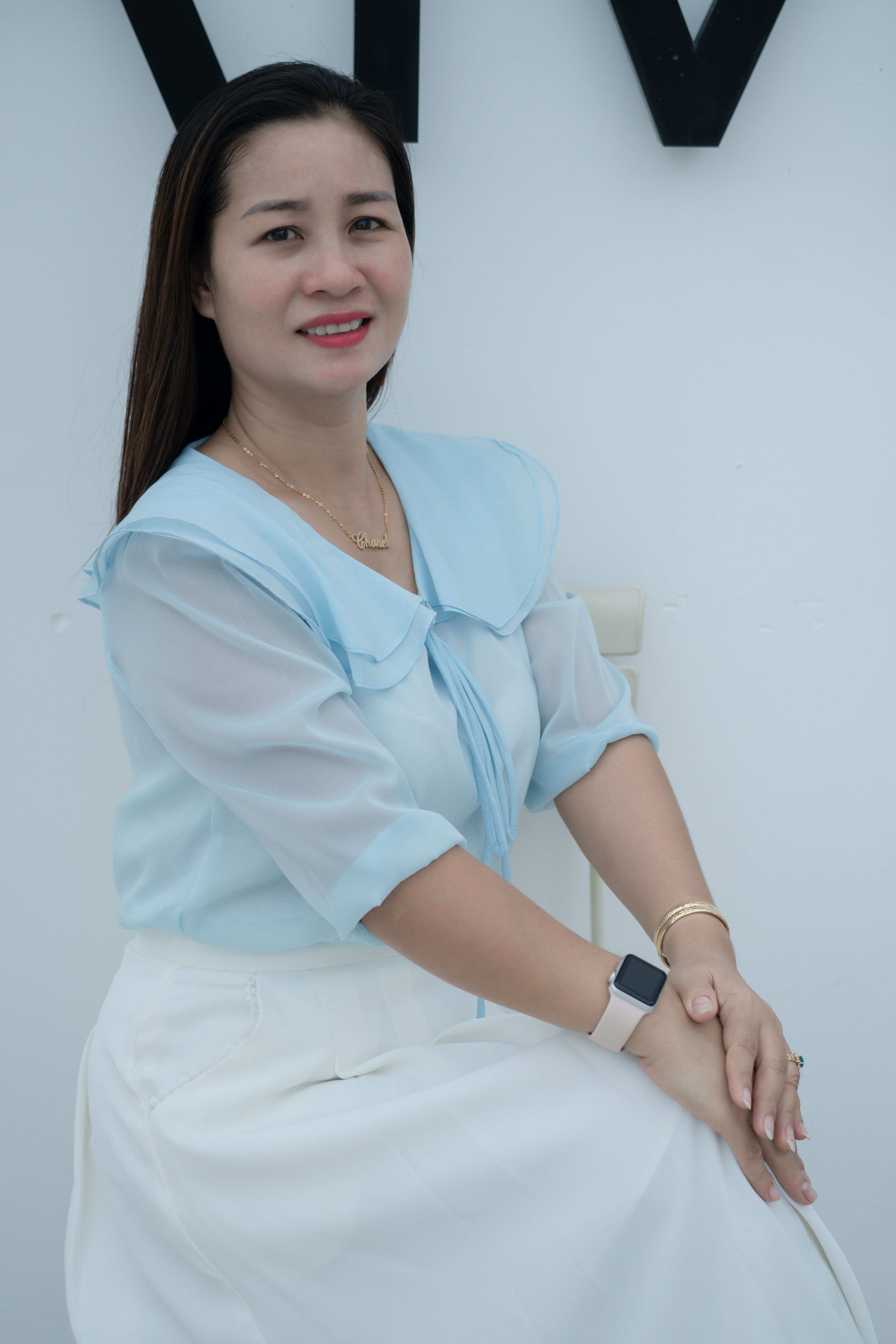 Charming woman in blue and white outfit posing indoors, showcasing elegance and style.