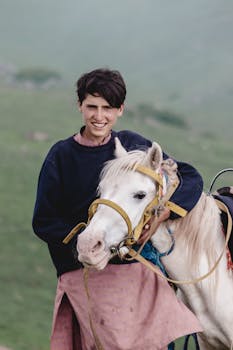 A smiling young man with a white horse in the scenic outdoors of Naran, Pakistan.