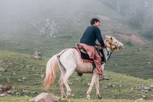 Free A man rides a white horse through the serene hills of Naran, Pakistan. Stock Photo
