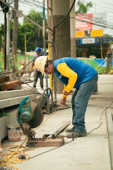 A construction worker uses a circular saw at an outdoor site, emphasizing skill and safety.