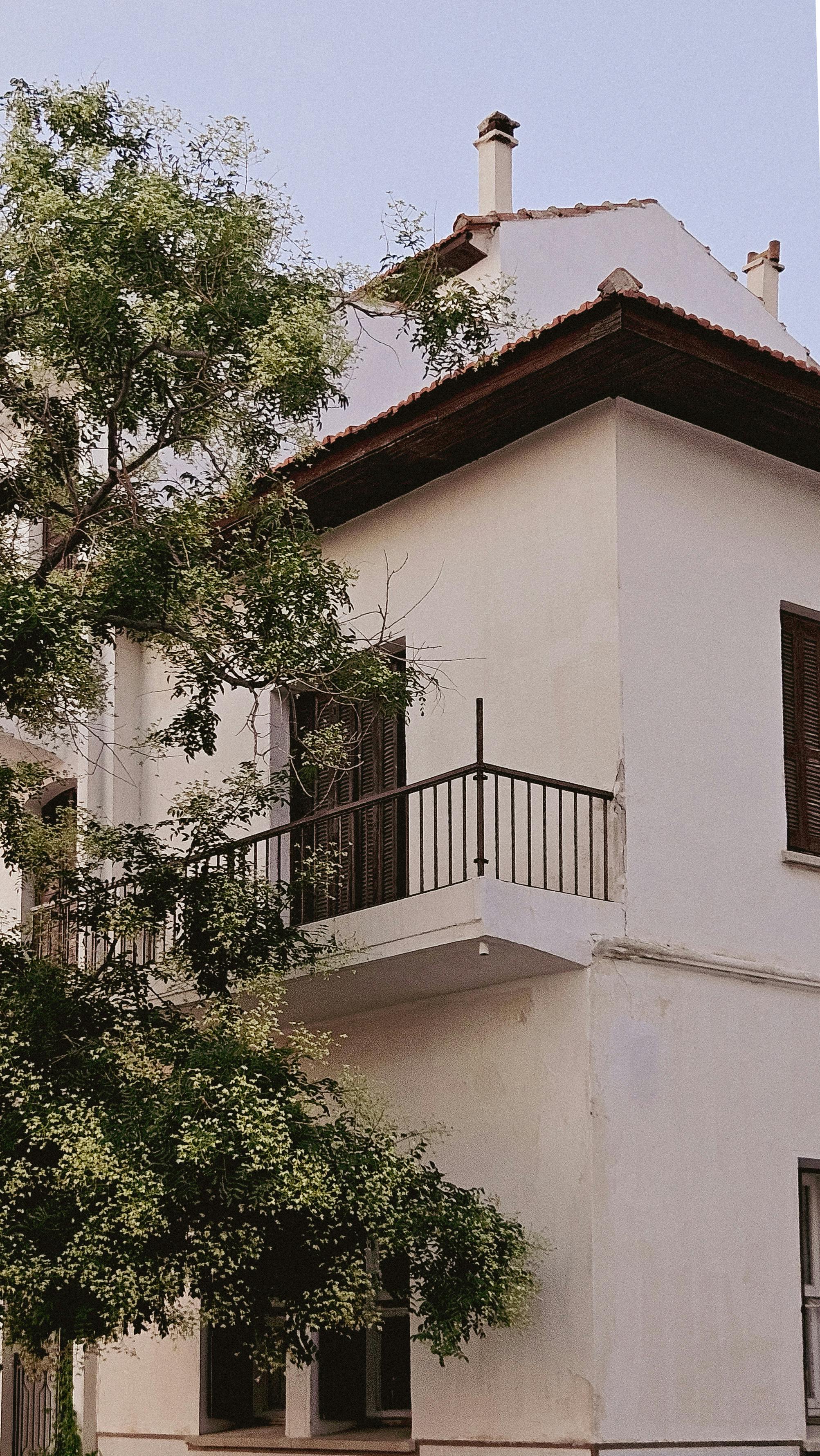 a white building with a balcony and trees