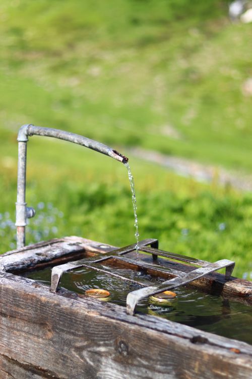 Free Flowing water from rustic faucet into trough outdoors in Montblanc. Stock Photo