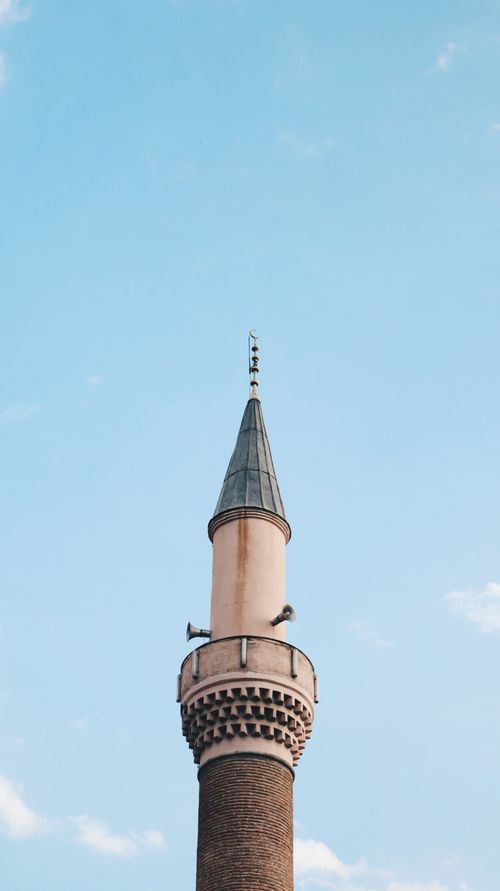 Free A beautiful minaret reaching towards an endless blue sky, showcasing traditional Islamic architecture. Stock Photo